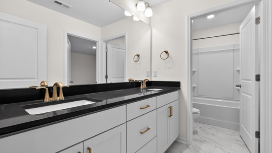 bathroom with dual vanity sinks white cabinets and quartz countertops