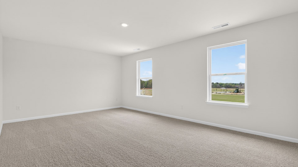 Primary bedroom with carpet floors and windows with access to the primary bathroom