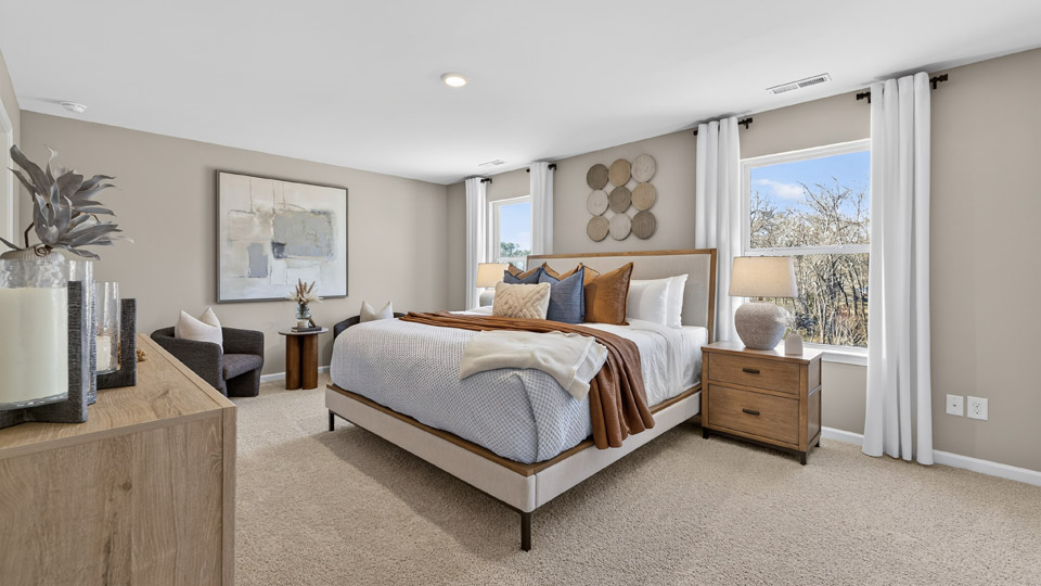 primary bedroom with two windows and carpeting, attached bath