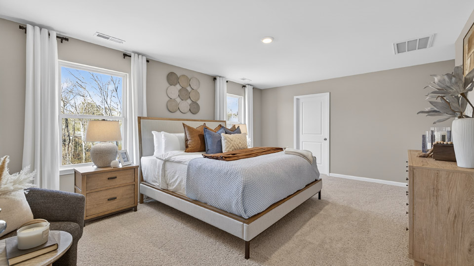 primary bedroom with two windows and carpeting, attached bath