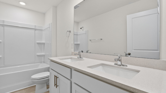 bathroom with tub shower combo and dual vanity
