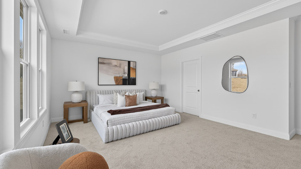 Primary bedroom with carpet floors and windows with access to the primary bathroom