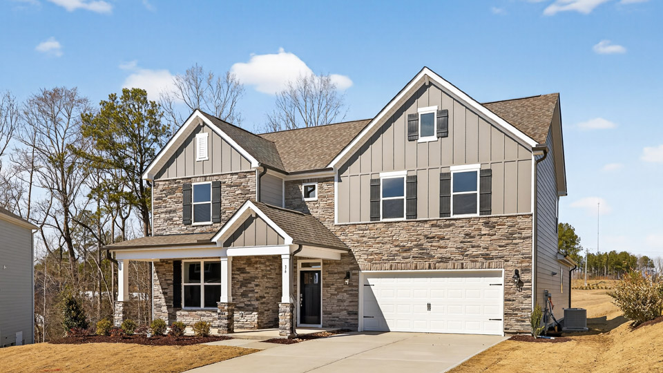 Two story home with brown colored siding with a two car garage