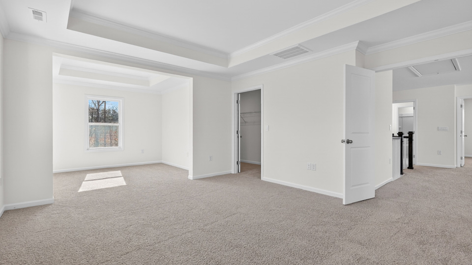 primary bedroom with two windows and carpeting, attached bath