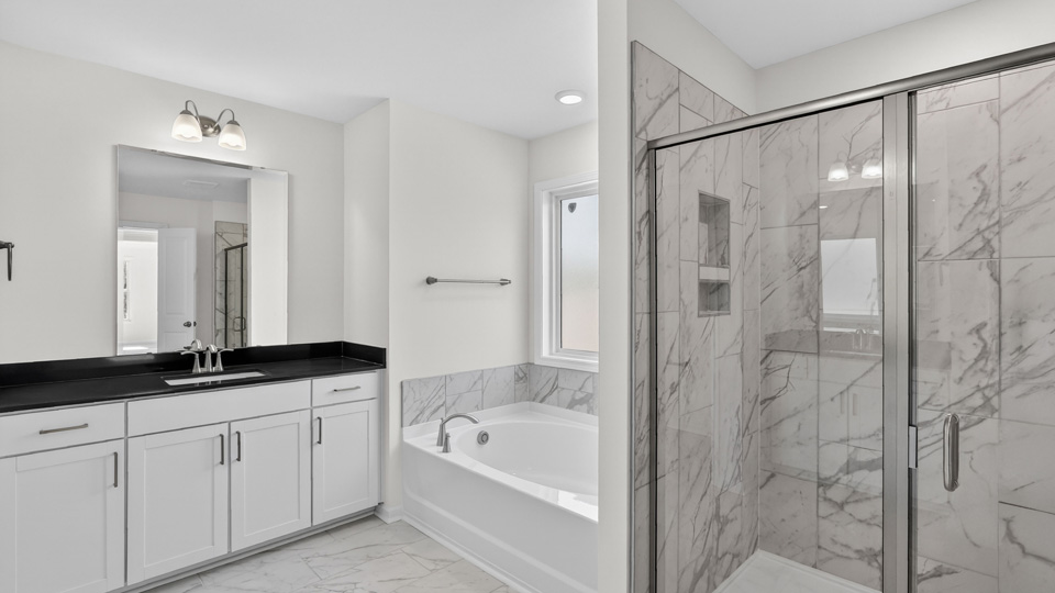 primary bathroom with walk in shower and dual vanity sinks