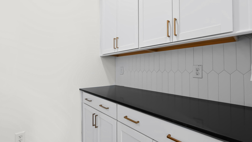 butlers pantry with quartz countertops and tile backsplash
