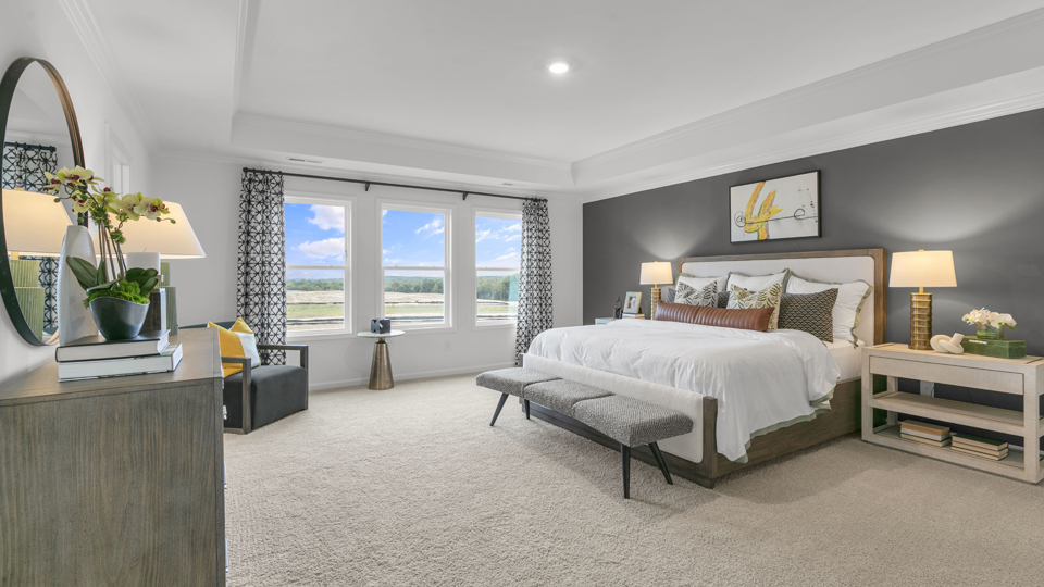 primary bedroom with two windows and carpeting, attached bath