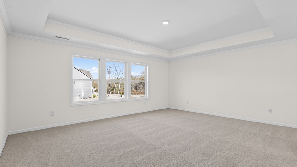 Primary bedroom with carpet floors and windows with access to the primary bathroom