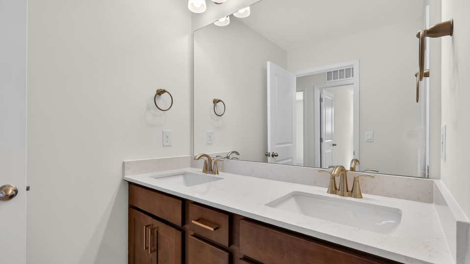 bathroom with brown cabinets dual vanity and quartz countertops