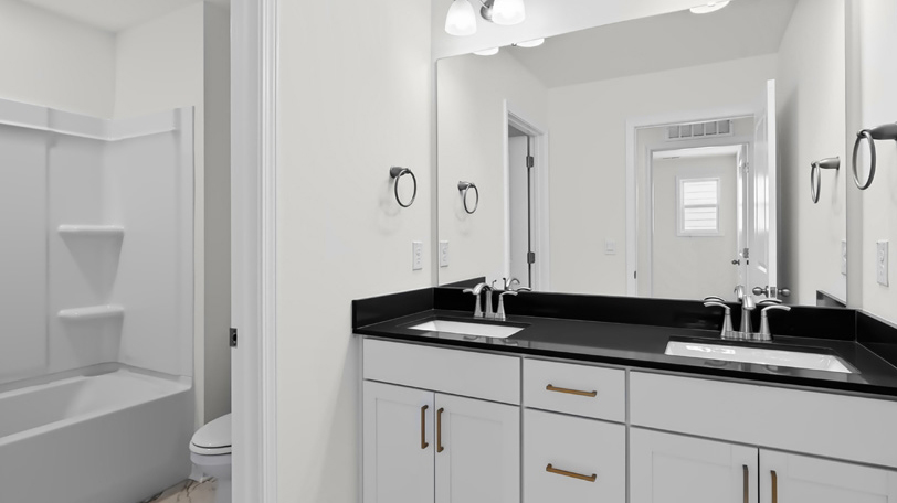 bathroom with dual vanity quartz countertops and whtie cabinets
