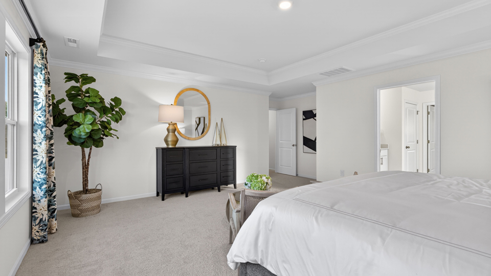primary bedroom with two windows and carpeting, attached bath
