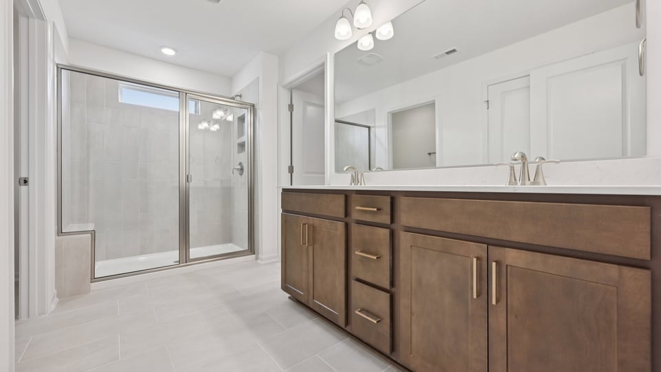 primary bathroom with dual vanity and walk in glass door shower