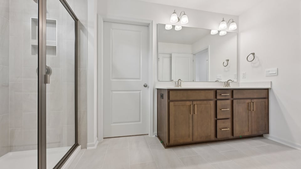 primary bathroom with dual vanity and walk in glass door shower