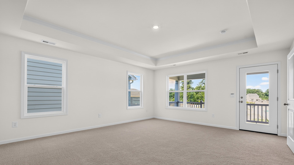 primary bedroom with tray ceiling and carpet flooring