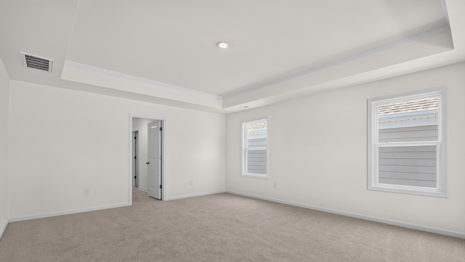 primary bedroom with carpet flooring and tray ceiling
