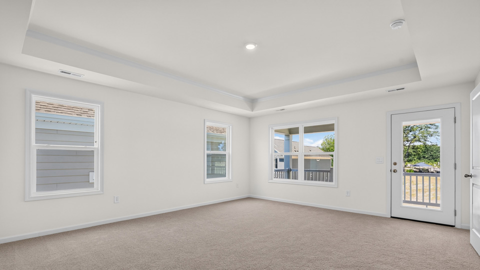 primary bedroom with carpet flooring and tray ceiling