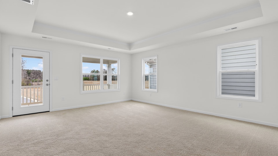 Primary bedroom with carpet floors and windows with access to the primary bathroom