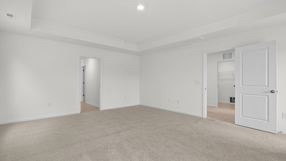 Primary bedroom with carpet floors and windows with access to the primary bathroom