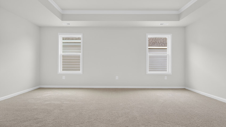 Primary bedroom with carpet floors and windows with access to the primary bathroom