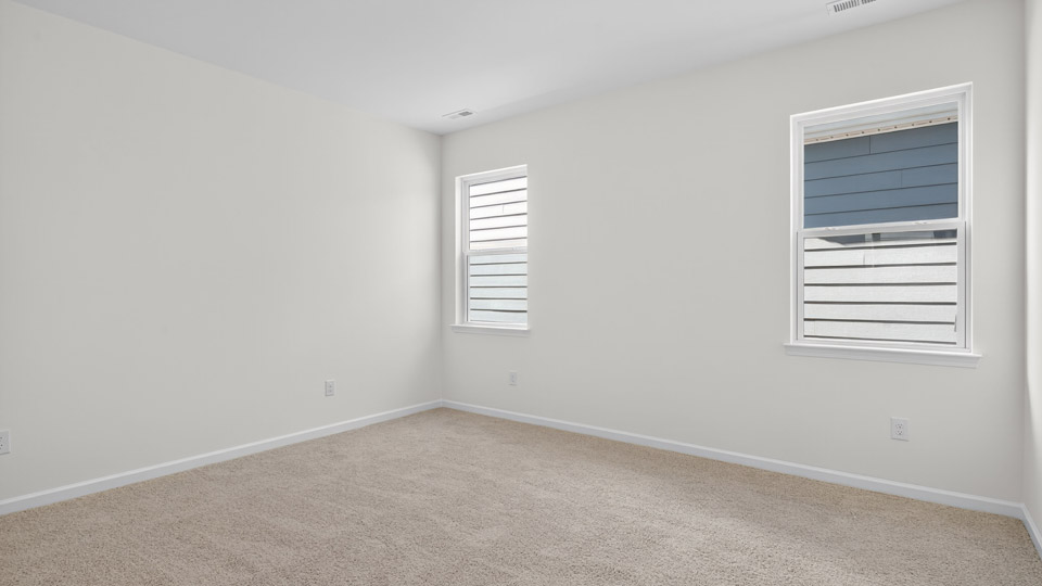 Primary bedroom with carpet floors and windows with access to the primary bathroom