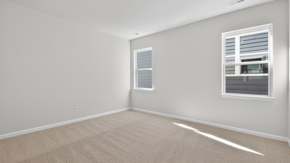 Primary bedroom with carpet floors and windows with access to the primary bathroom