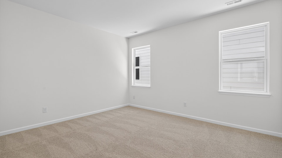 Primary bedroom with carpet floors and windows with access to the primary bathroom