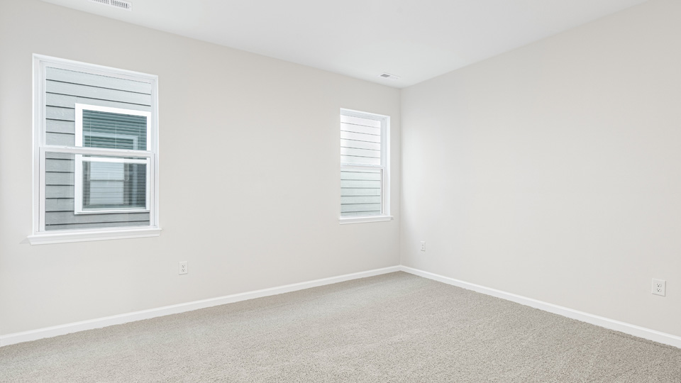 primary bedroom with two windows and carpeting, attached bath