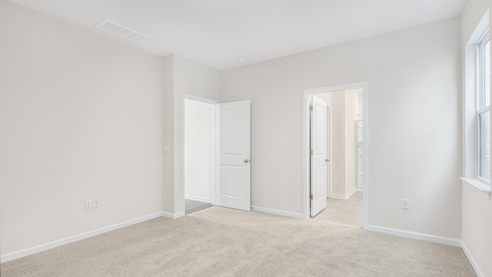 primary bedroom with two windows and carpeting, attached bath