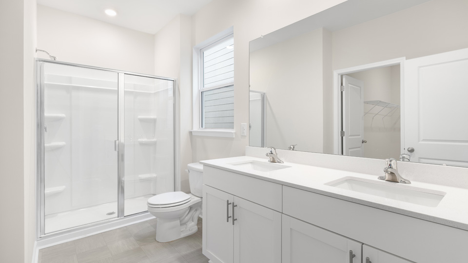 primary bathroom with walk in shower and dual vanity sinks