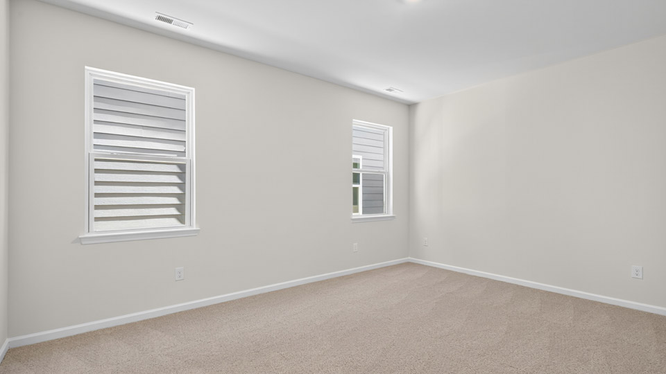 Primary bedroom with carpet floors and windows with access to the primary bathroom