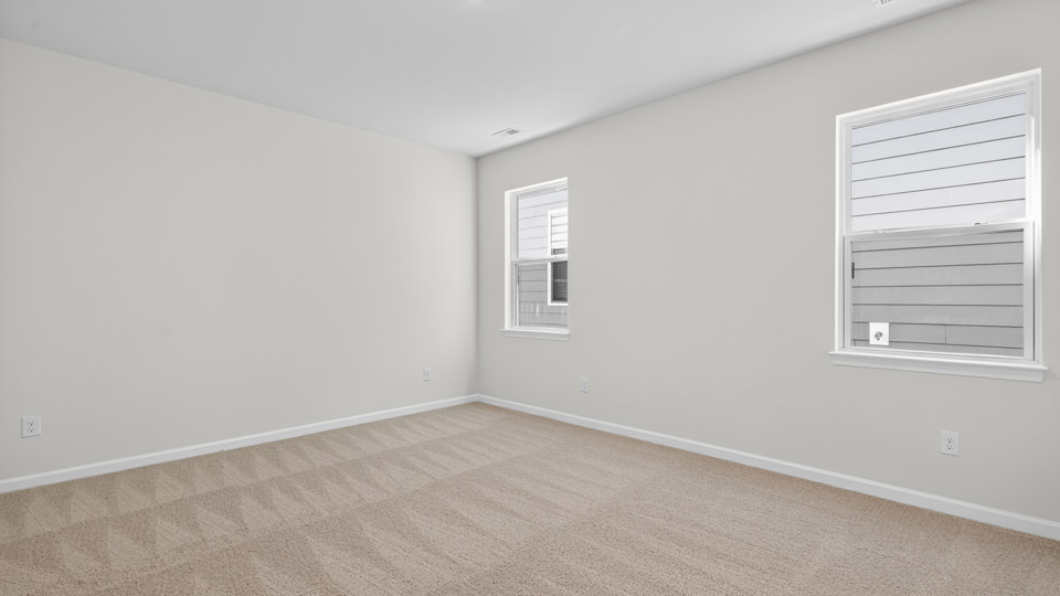Primary bedroom with carpet floors and windows with access to the primary bathroom