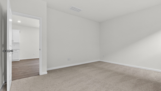primary bedroom with two windows and carpeting, attached bath