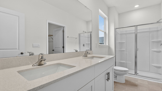 primary bathroom with walk in shower and dual vanity sinks