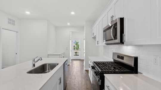 kitchen with quartz counters, kitchen island, pantry, stainless steel appliances