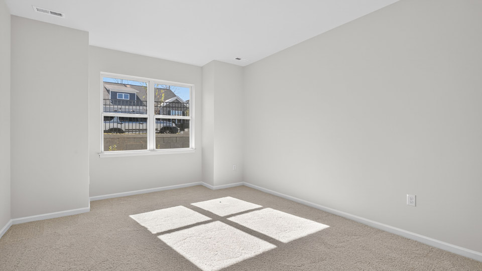 Primary bedroom with carpet floors and windows with access to the primary bathroom