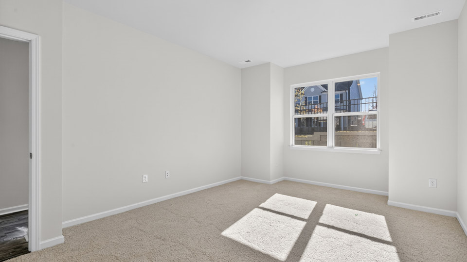 Primary bedroom with carpet floors and windows with access to the primary bathroom