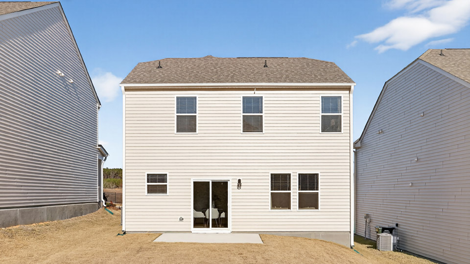 Two story home with white siding and back patio.