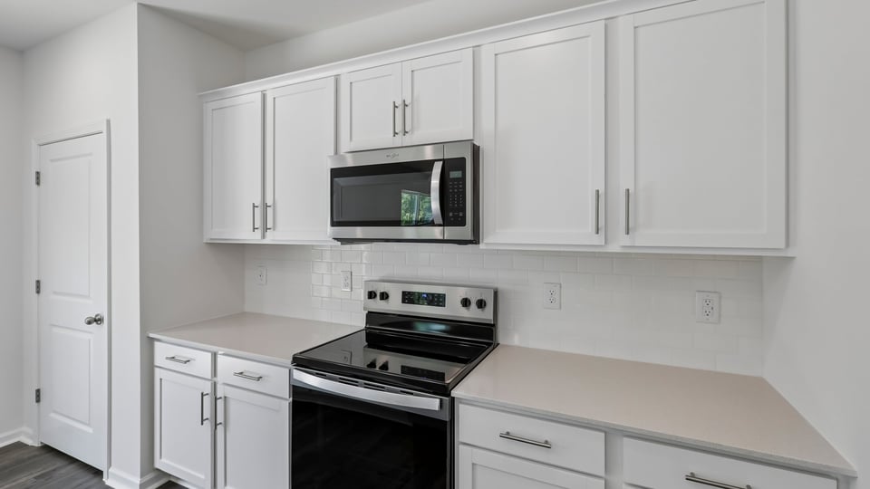 kitchen with quartz counters, kitchen island, pantry, stainless steel appliances