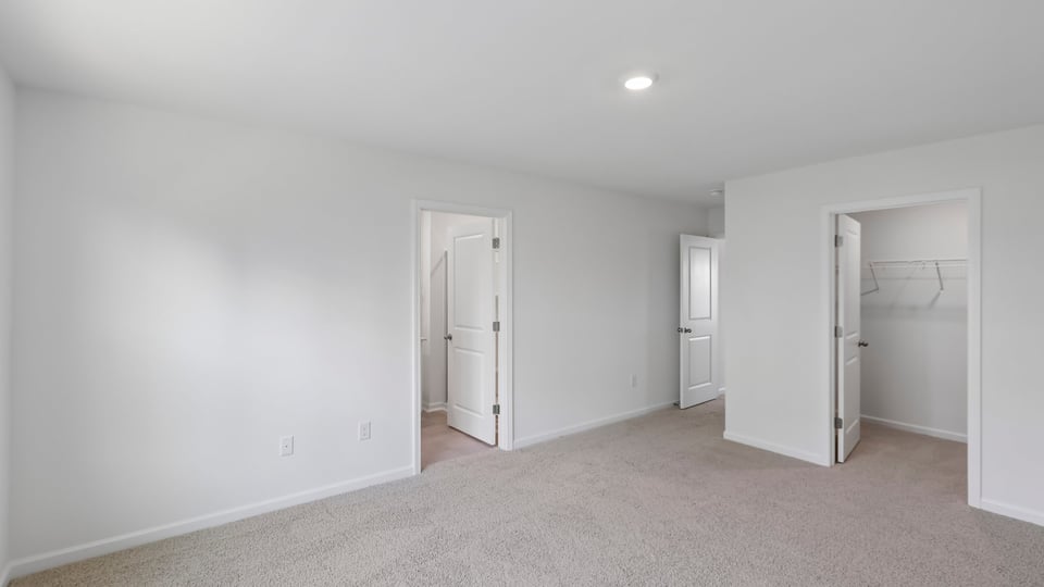 primary bedroom with two windows and carpeting, attached bath