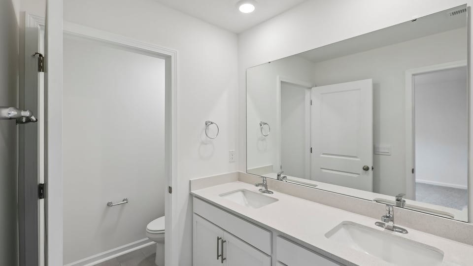 primary bathroom with walk in shower and dual vanity sinks
