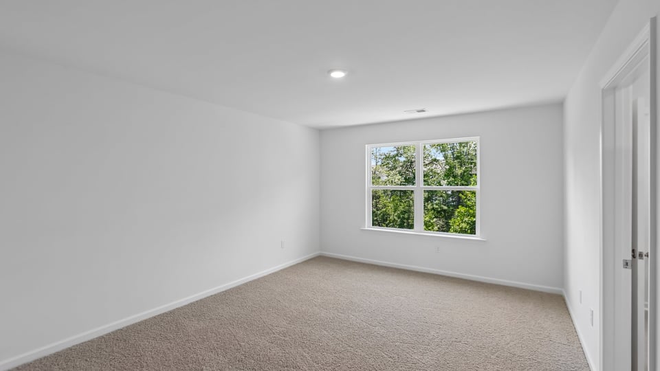 primary bedroom with two windows and carpeting, attached bath