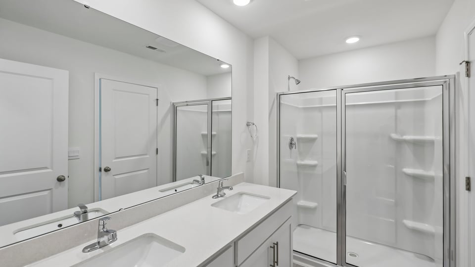 primary bathroom with walk in shower and dual vanity sinks