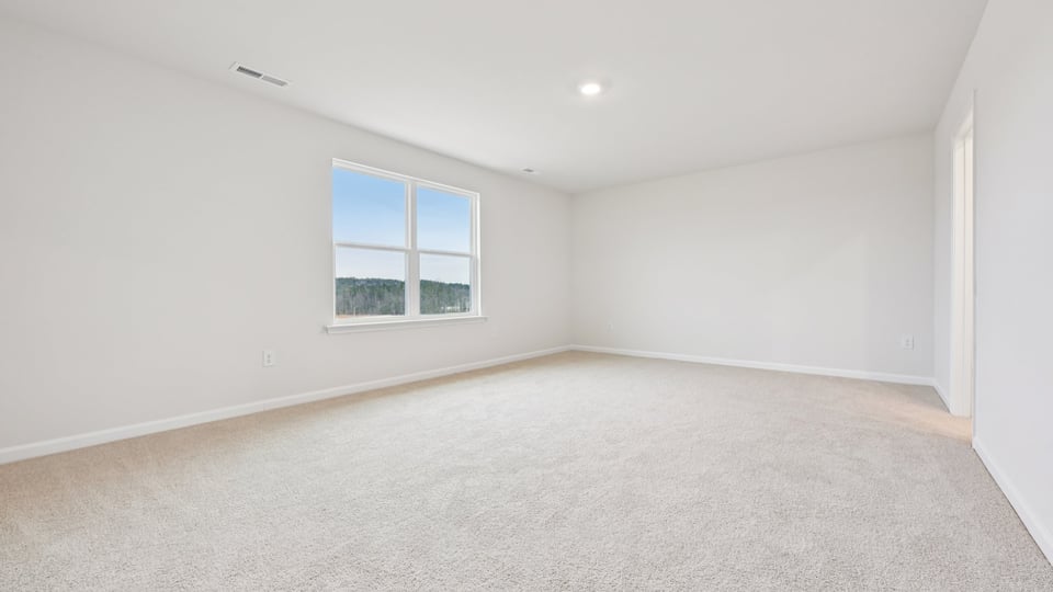 primary bedroom with two windows and carpeting, attached bath