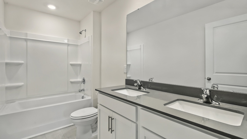 bathroom with dual vanity and tub shower combo