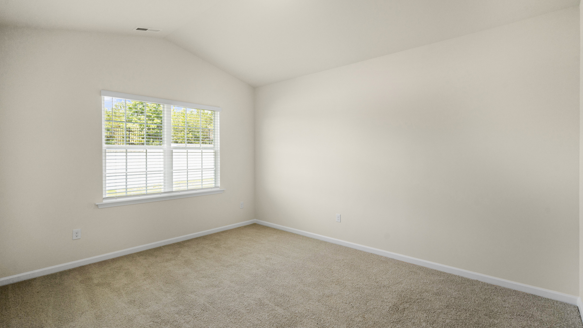 primary bedroom with two windows and carpeting, attached bath