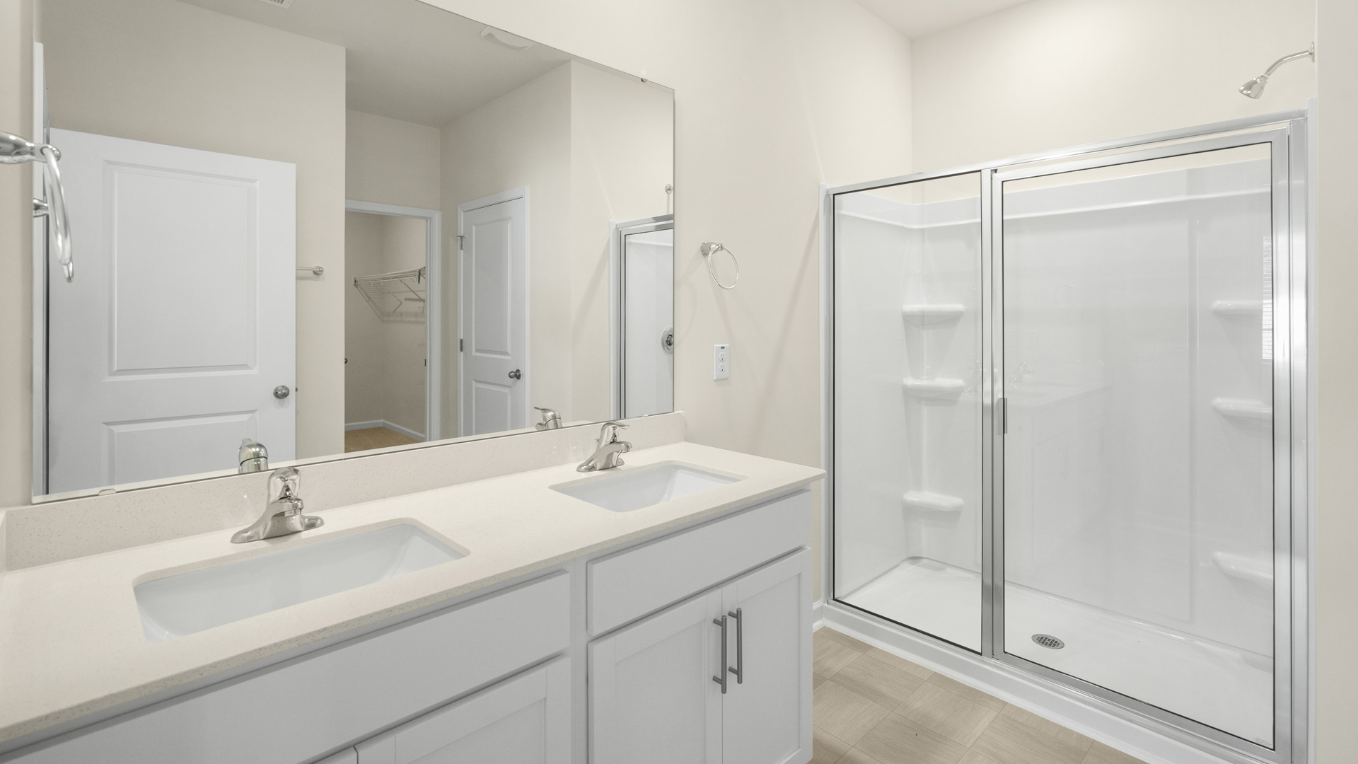 primary bathroom with walk in shower and dual vanity sinks