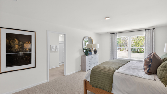 primary bedroom with two windows and carpeting, attached bath