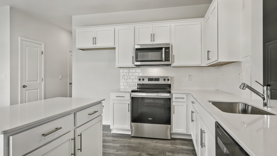 kitchen with quartz counters, kitchen island, pantry, stainless steel appliances