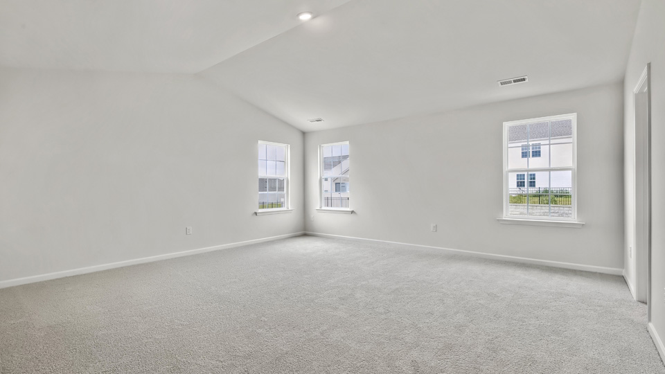 primary bedroom with two windows and carpeting, attached bath