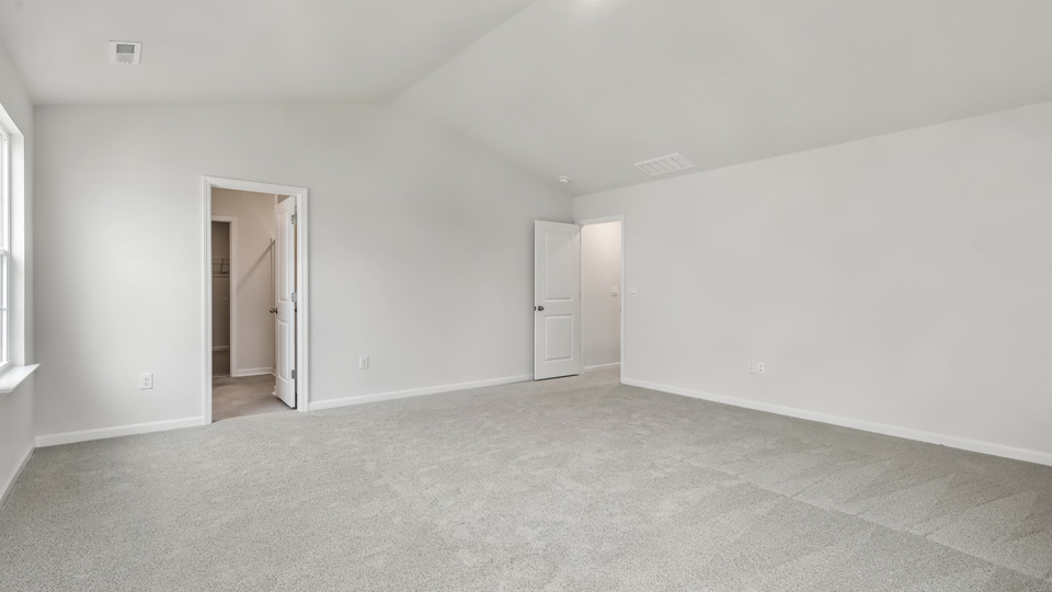 primary bedroom with two windows and carpeting, attached bath